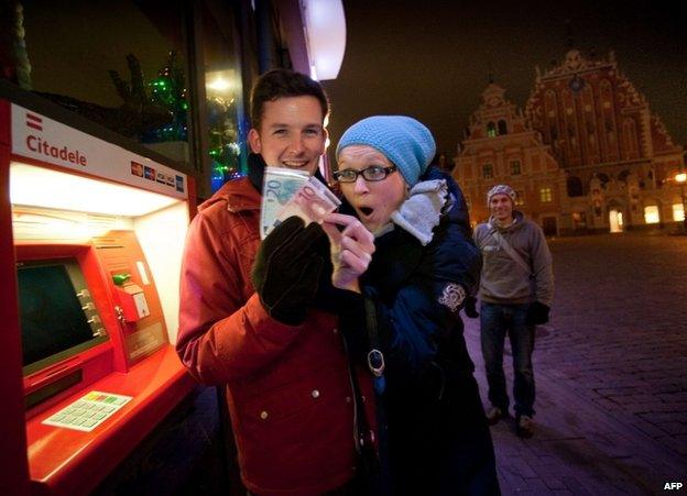 A man and woman withdraw euros from a cash machine in Riga, 1 January