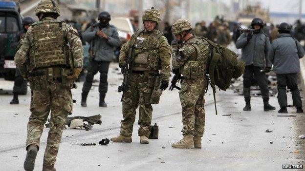 NATO troops and Afghan policemen inspect at the site of a bomb attack in Kabul December 27, 2013