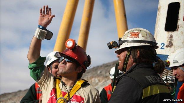 Chilean miner Alex Vega (left), the 10th of 33 miners to leave the mine, waves upon surfacing from the San Jose mine, near Copiapo, on 13 October, 2010