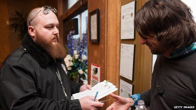 Head of security Kurt Britz (L) checks the driver's licence of Adam Hartle of Jacksonville, Florida at the 3-D Denver Discrete Dispensary 1 January 2014