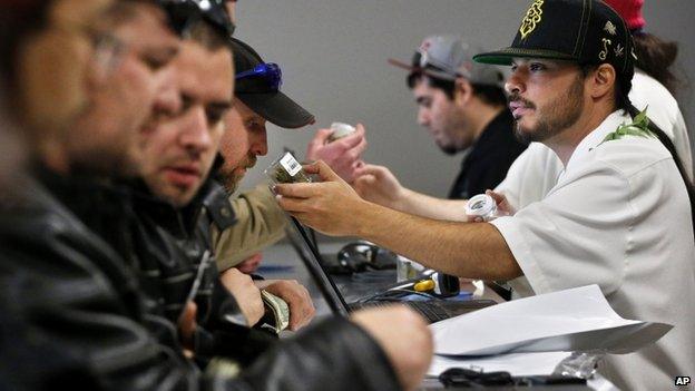 Employee David Marlow, right, helps a customer, who smells a strain of marijuana before buying it, at the crowded sales counter inside Medicine Man marijuana retail store, which opened as a legal recreational retail outlet in Denver 1 January 2014