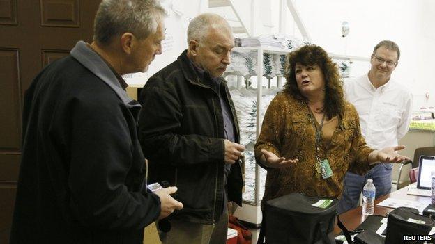 Cheri Hackett, (2nd right) co-owner of the Botana Care marijuana store talks to Colorado Marijuana Enforcement officials (L) just before opening her doors to customers for the first time in Northglenn, Colorado 1 January 2014