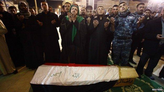 Mourners in the Shia holy city of Najaf pray near the coffin of a soldier killed in Anbar (2 January 2014)