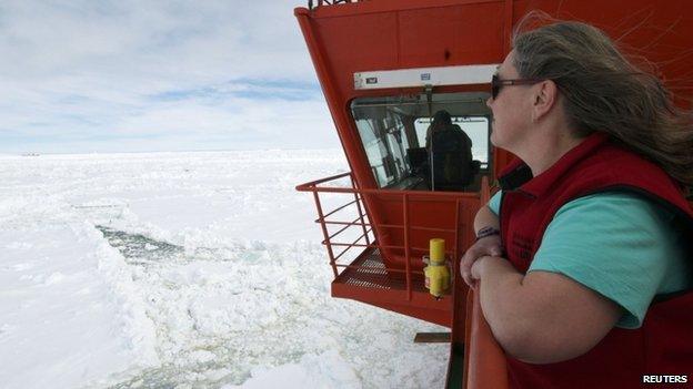 A woman stands on the deck of the Aurora Australis, as the Xue Long Chinese icebreaker is seen in the distance sitting in an ice pack