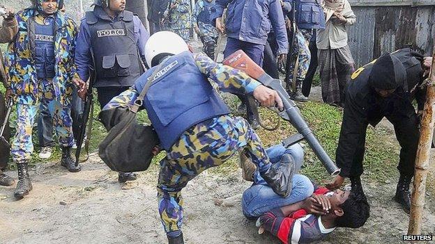 A police officer kicks a protester during a clash after protesters attacked and set fire to polling booths in Bogra January 5, 2014