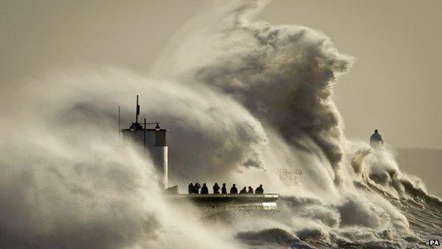 People watch and photograph enormous waves as they break on Porthcawl harbour, South Wales