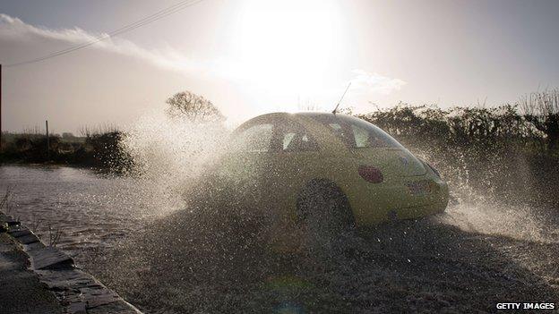 A motorist steers his vehicle along a flooded road in the village of Buscot Wick, near Oxford,