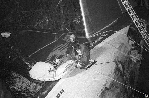 Rescuers sitting on top of the plane take a break