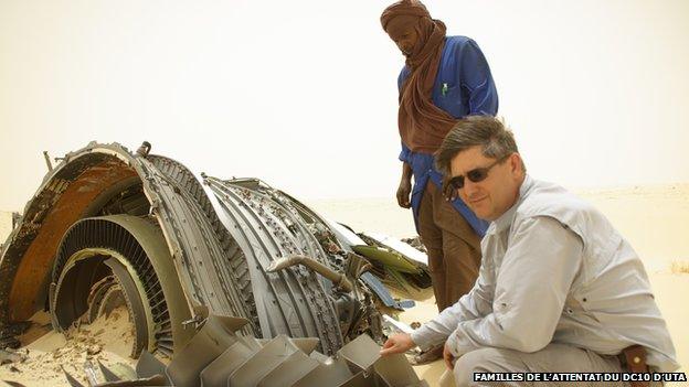 Denoix de Saint Marc kneels next to an engine part lying in the desert