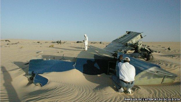 man kneels next to some of the wreckage