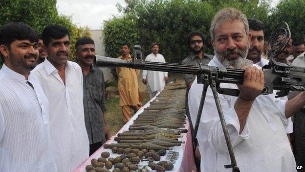 In this picture taken on May 11, 2012, Pakistan's senior police investigator Chaudhry Aslam holds a machine gun recovered from militants with other ammunition in Karachi, Pakistan.