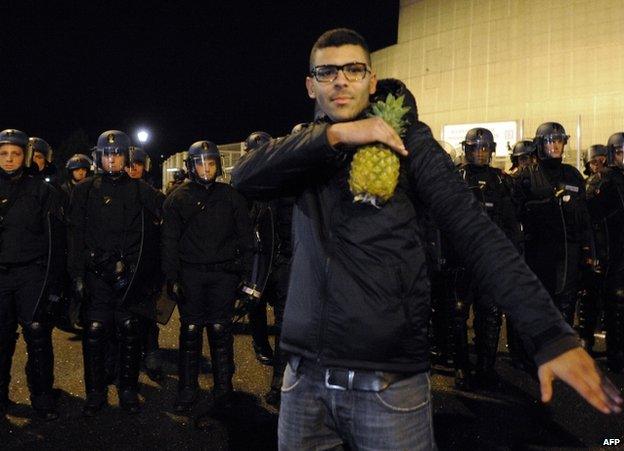 A man holds a pineapple and makes a quenelle salute outside the Zenith concert hall in Nantes, 9 January