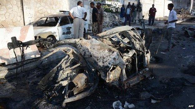 Somali residents look at the wreckage of two cars on 2 January 2014 in Mogadishu