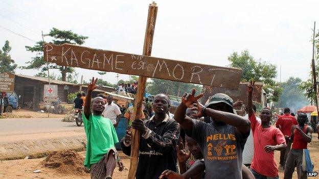 Residents in Goma hold a cross saying "Kagame is dead" on hearing false rumours that the Rwandan president had died