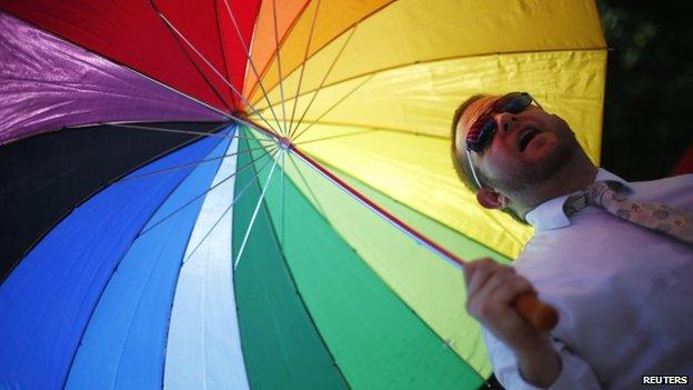 A man under a multi-coloured umbrella