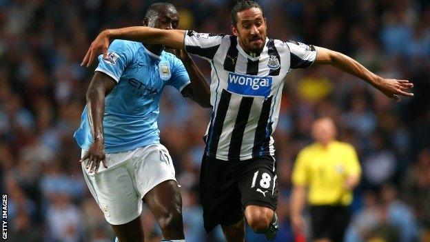 Jonas Gutierrez of Newcastle United holds off a challenge from Yaya Toure of Manchester City