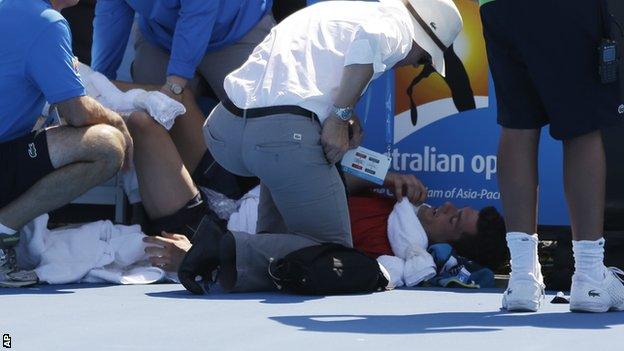 Frank Dancevic of Canada lies on the court after collapsing during his first round match against Benoit Paire of France