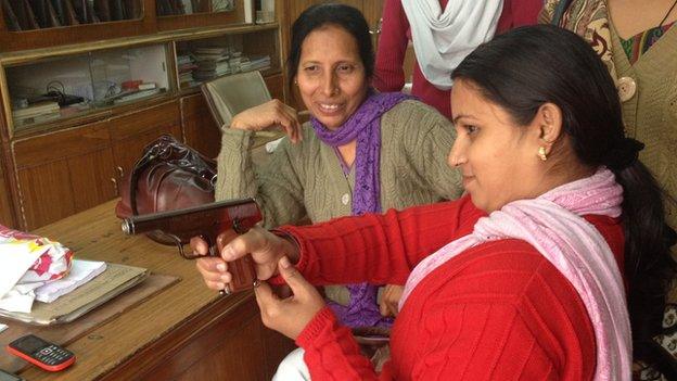 A woman tries out a pistol in a gun shop in Kanpur