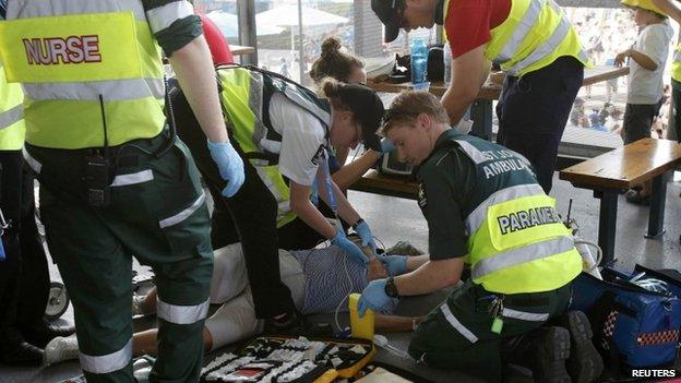 Medics attend to a man who collapsed due to overheating at the Australian Open 2014 tennis tournament in Melbourne, 14 January 2014