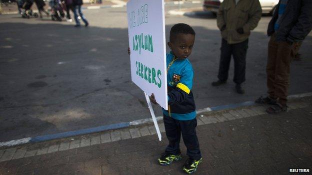 A child from the African migrant community holds a placard ahead of a protest against Israel's detention policy toward migrants, in Tel Aviv (15 January 2014)