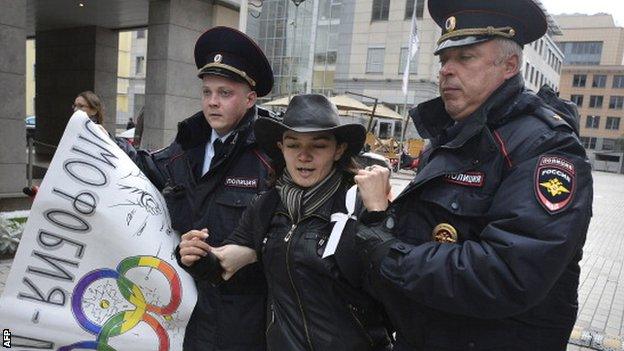 A protester is led away by Russian police officers