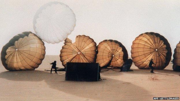 Paratroopers land in the desert with their parachutes