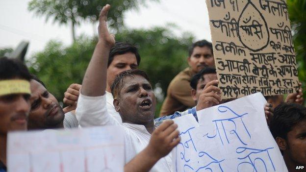 Indian men stand outside a court in India demanding the death penalty of four men convicted of rape and murder in Delhi.