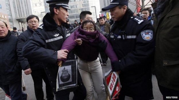 Liu Chunxia, a supporter of Xu Zhiyong, is detained by policemen while she gathers with other supporters nearby a court where Mr Xu's trial is being held in Beijing, 22 January 2014