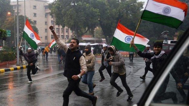 Supporters of New Delhi chief minister, Arvind Kejriwal carry Indian flags as they run close to the area where Kejriwal spent the night during a sit-in protest in New Delhi on January 21, 2014