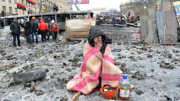 A protester smokes at the barricade in front of armour-clad security forces blocking access to the Verkhovna Rada parliament in Kiev