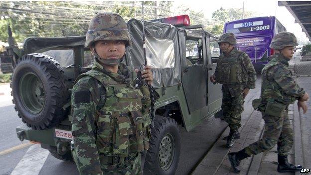 Thai soldiers stand guard at an intersection following the government's announcement of a state of emergency in Bangkok on 22 January 2014