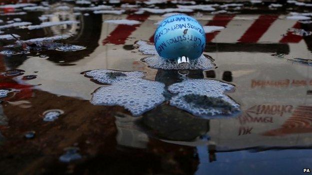 Reflection of van driving past Christmas bauble floating in water