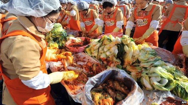 South Korean volunteers make kimchi, a traditional Korean dish of spicy fermented cabbage and radish, in a park outside the metropolitan government building in Seoul, 15 November 2012