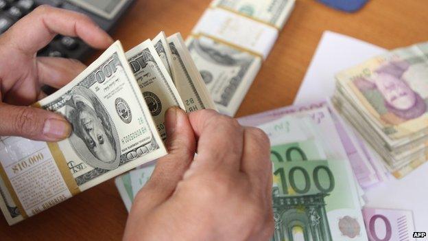 Man counts money, including dollars, euros and Iranian rials