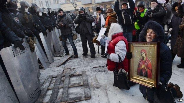 Women holding icons kneel in front of riot police in Kiev. Photo: 24 January 2014