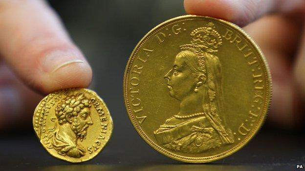 A coin from the reign of Emperor Marcus Aurelius and a £5 Victoria coin