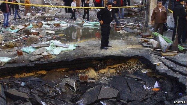 A police officer inspects a crater made after a bomb attack