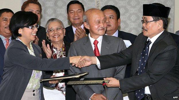 Miriam Coronel Ferrer (L), chairperson of the government negotiating panel, exchanges documents with MILF Chief Negotiator Monagher Iqbal (R) during a press conference at a hotel in Kuala Lumpur on January 25, 2014.