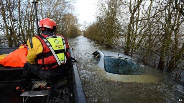 Members of the Avon and Somerset Police Underwater Search Unit inspect a submerged abandoned car as they head to the village of Muchelney in Somerset