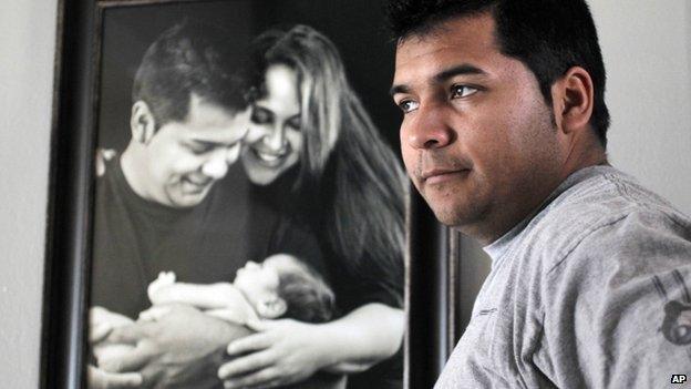 Erick Munoz stands with an undated copy of a photograph of himself with wife Marlise and their son Mateo, in Haltom City, Texas