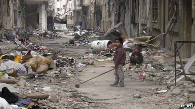 A child clears damage and debris in the besieged area of Homs on 26 January 2014