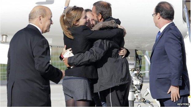 Former French hostage Daniel Larribe is welcomed by relatives as President Francois Hollande (far right) and Defence Minister Jean-Yves Le Drian look on