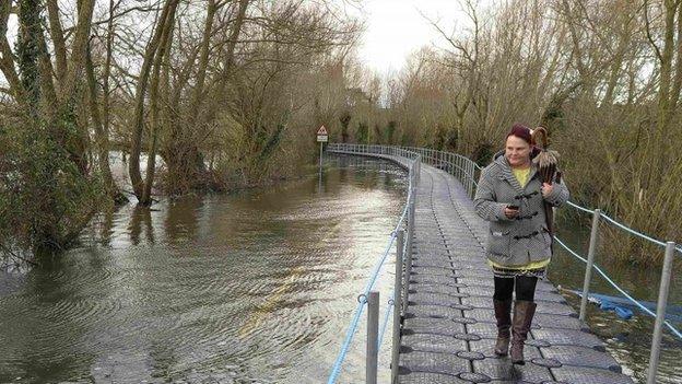 A woman walks along a temporary floating pontoon in Muchelney