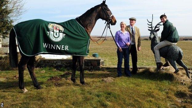 Auroras Encore with trainers Harvey and Sue Smith and winning jockey Ryan Mania sitting on a stone stag at Craiglands Farm, Bingley