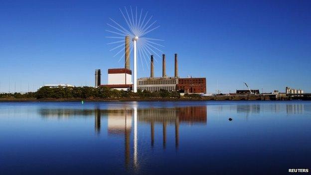 A Massachusetts Water Resources Authority wind turbine turns in front of a 1951 megawatt fossil fuel power plant in Charlestown, Massachusetts