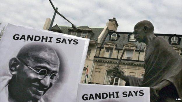 Peace activists hold signs with pictures of the late Indian leader Mohandas Karamchand Gandhi under his statue in front of the Indian Embassy in Washington.