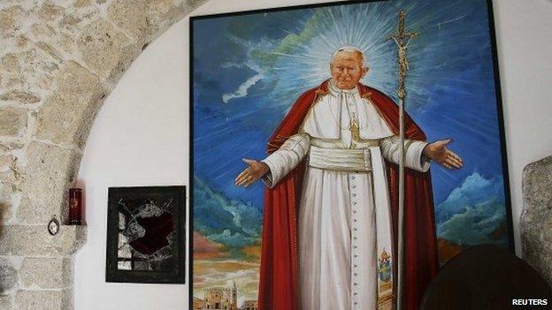 A broken glass of a niche where the reliquary with the blood of the late Pope John Paul II was located is seen next to a painting of the late Pope in the small mountain church of San Pietro della Ienca,