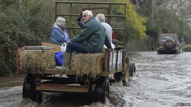 A tractor carries residents along a flooded road from the village of Thorney on the Somerset Levels