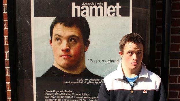 Tommy stands outside Hamlet poster