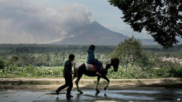 A tourist rides a horse as Sinabung spews volcanic materials in Gundaling, January 21